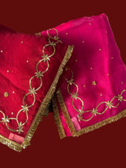 A close-up of a bright pink and red Saree, featuring gold floral embroidery, a gold fringe border by House of baisa