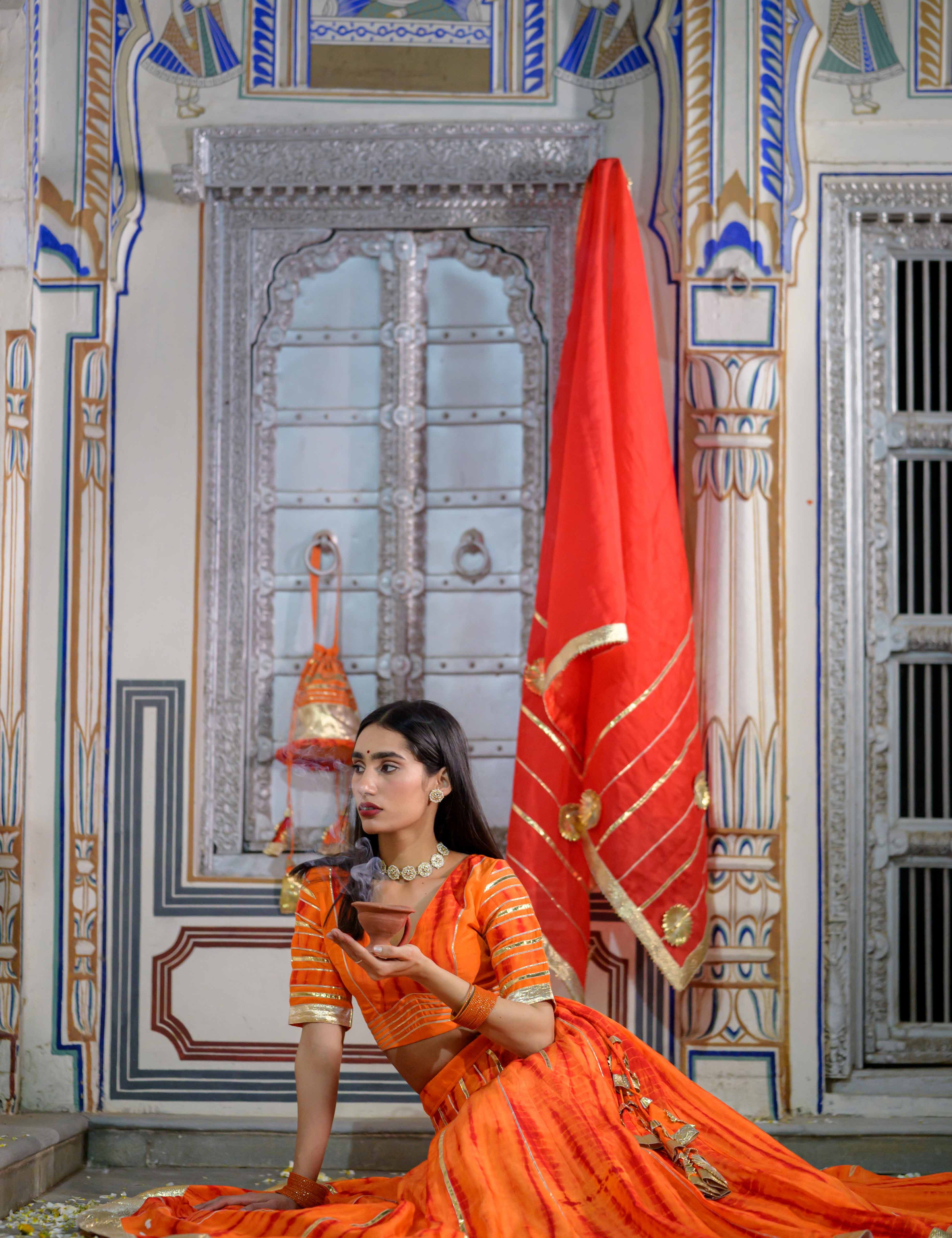 Model wearing festive orange lehenga from House of Baisa

