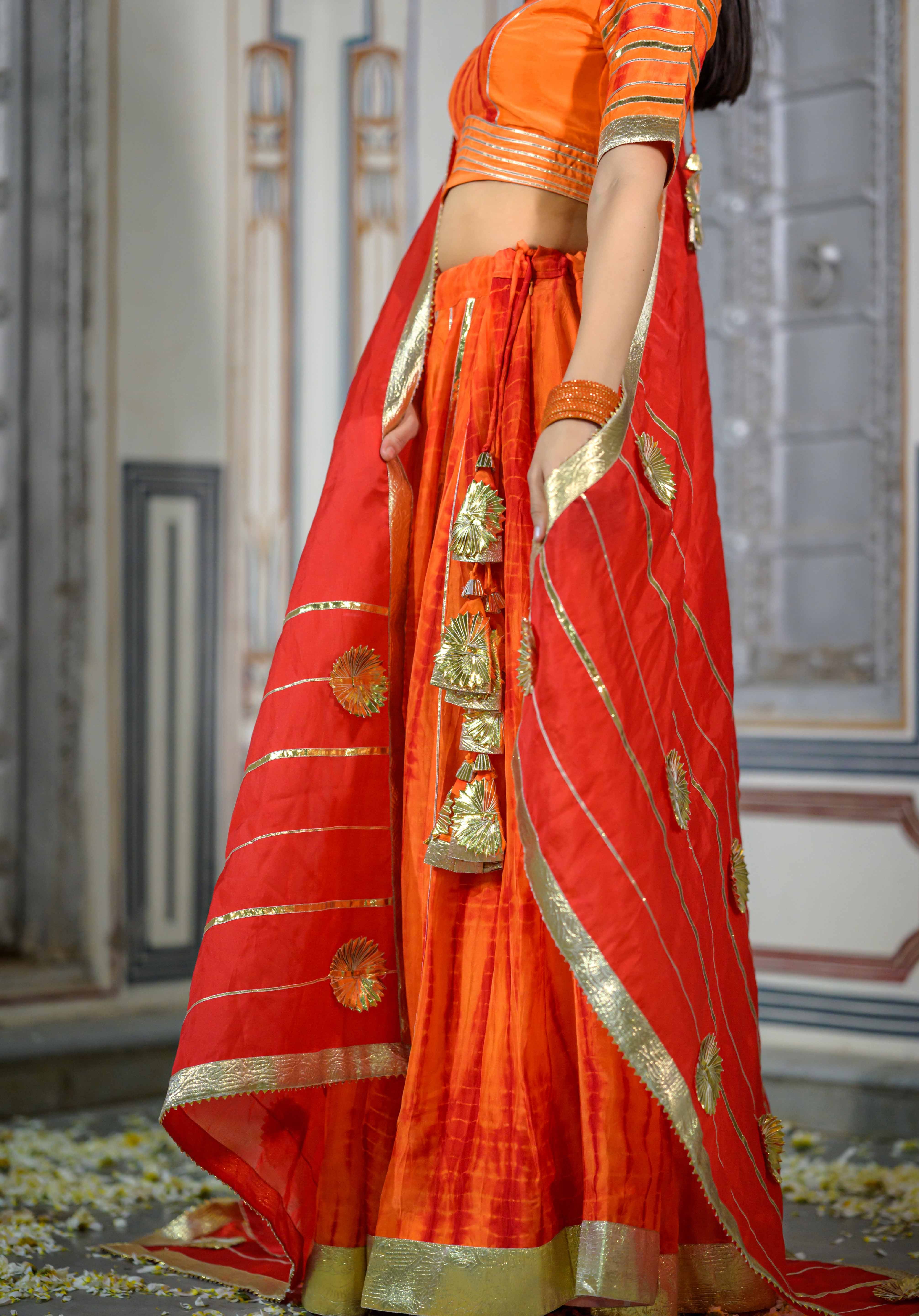House of Baisa model showcasing vibrant orange satin lehenga.