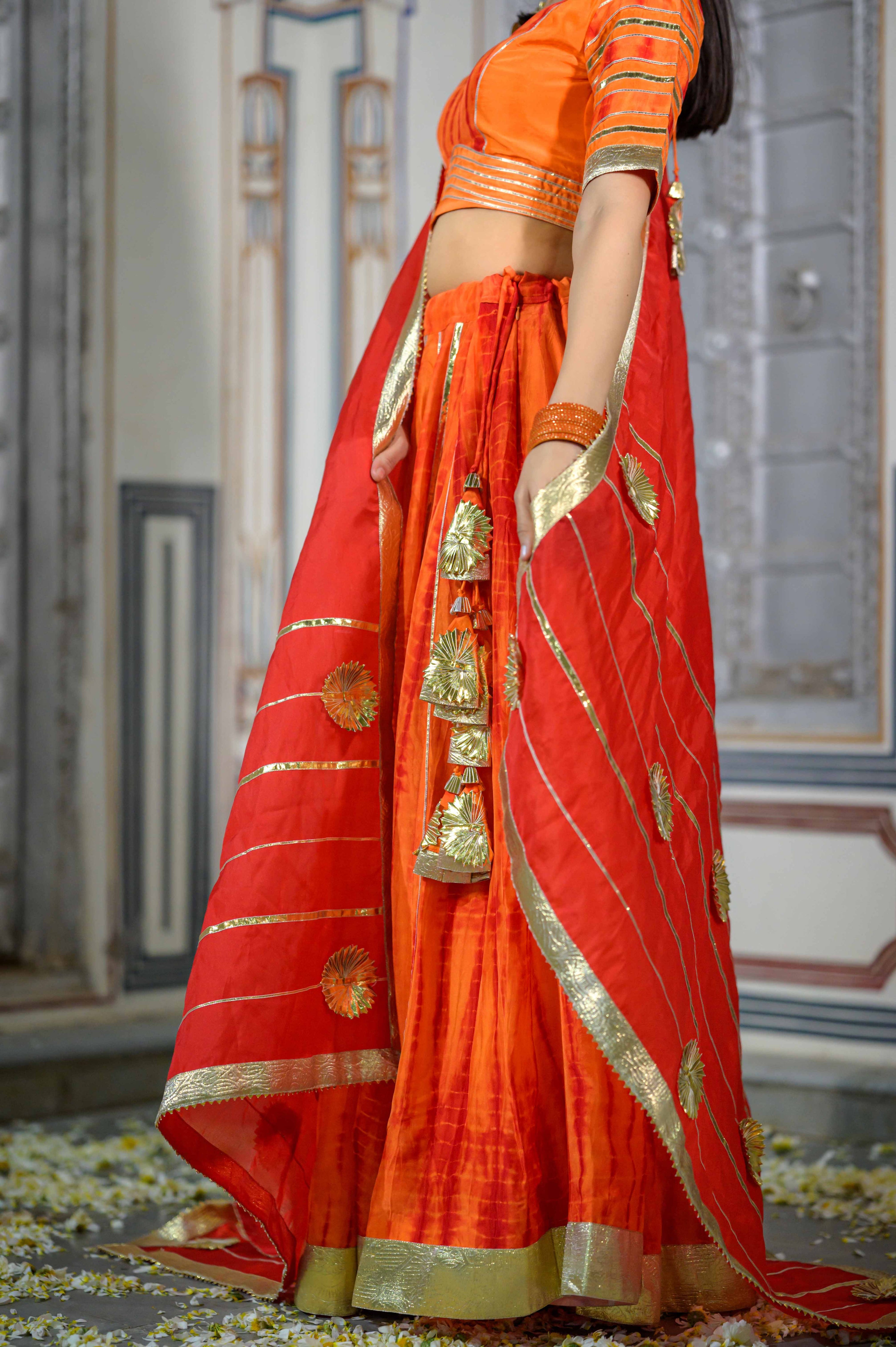 House of Baisa model showcasing vibrant orange satin lehenga.