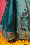 Side pose of model in teal lehenga with floral border	