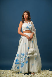 Woman wearing blue lehenga with white floral painting
