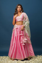 Model twirling in satin pink lehenga with net dupatta
