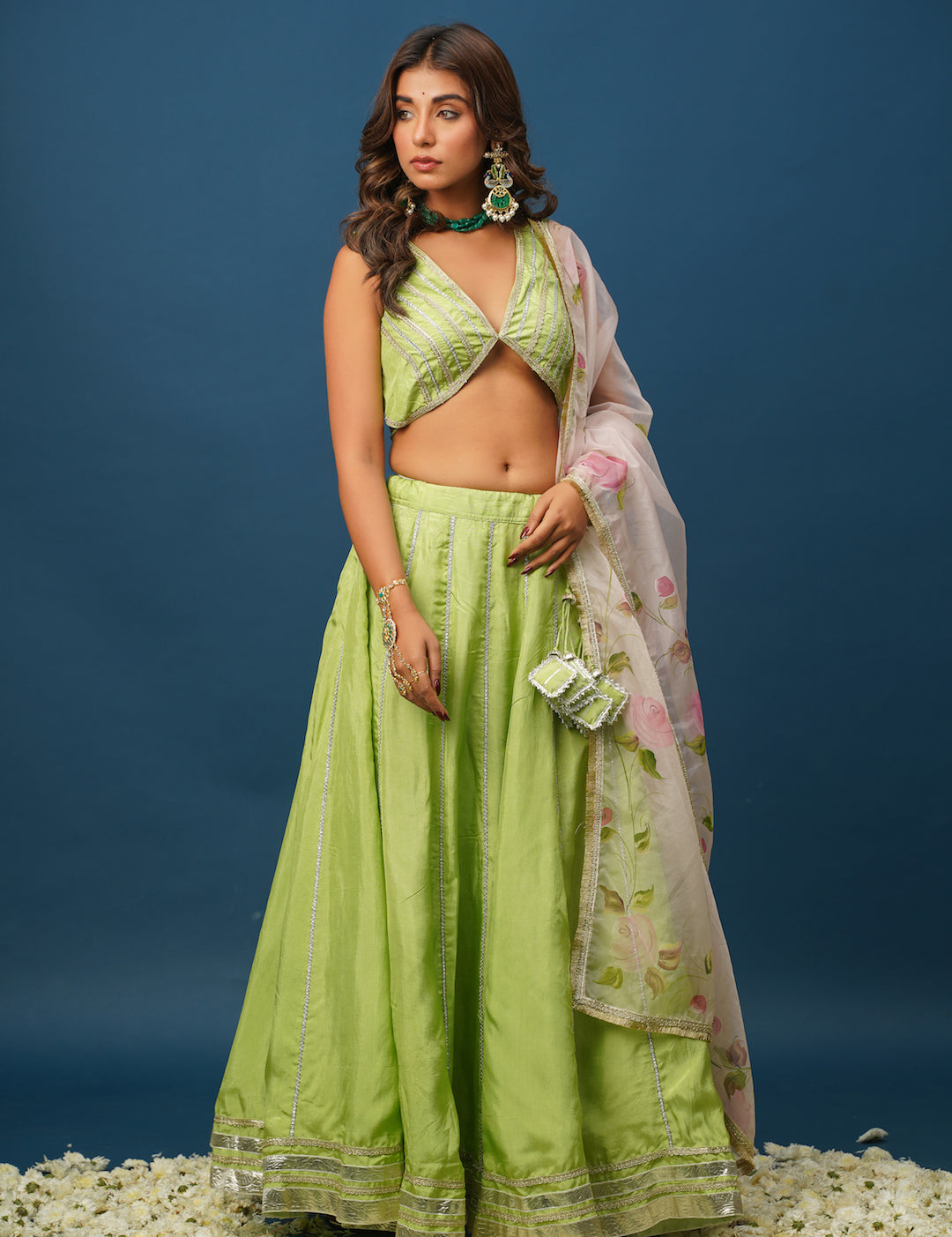 Close-up of hand-painted floral work on green lehenga skirt
