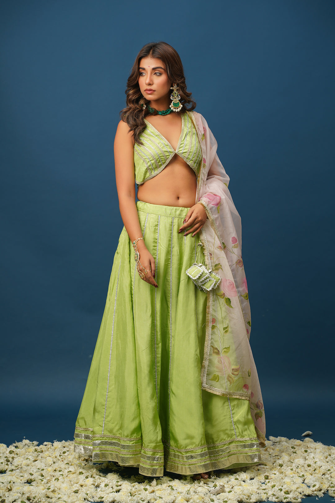 Close-up of hand-painted floral work on green lehenga skirt
