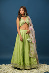 Close-up of hand-painted floral work on green lehenga skirt
