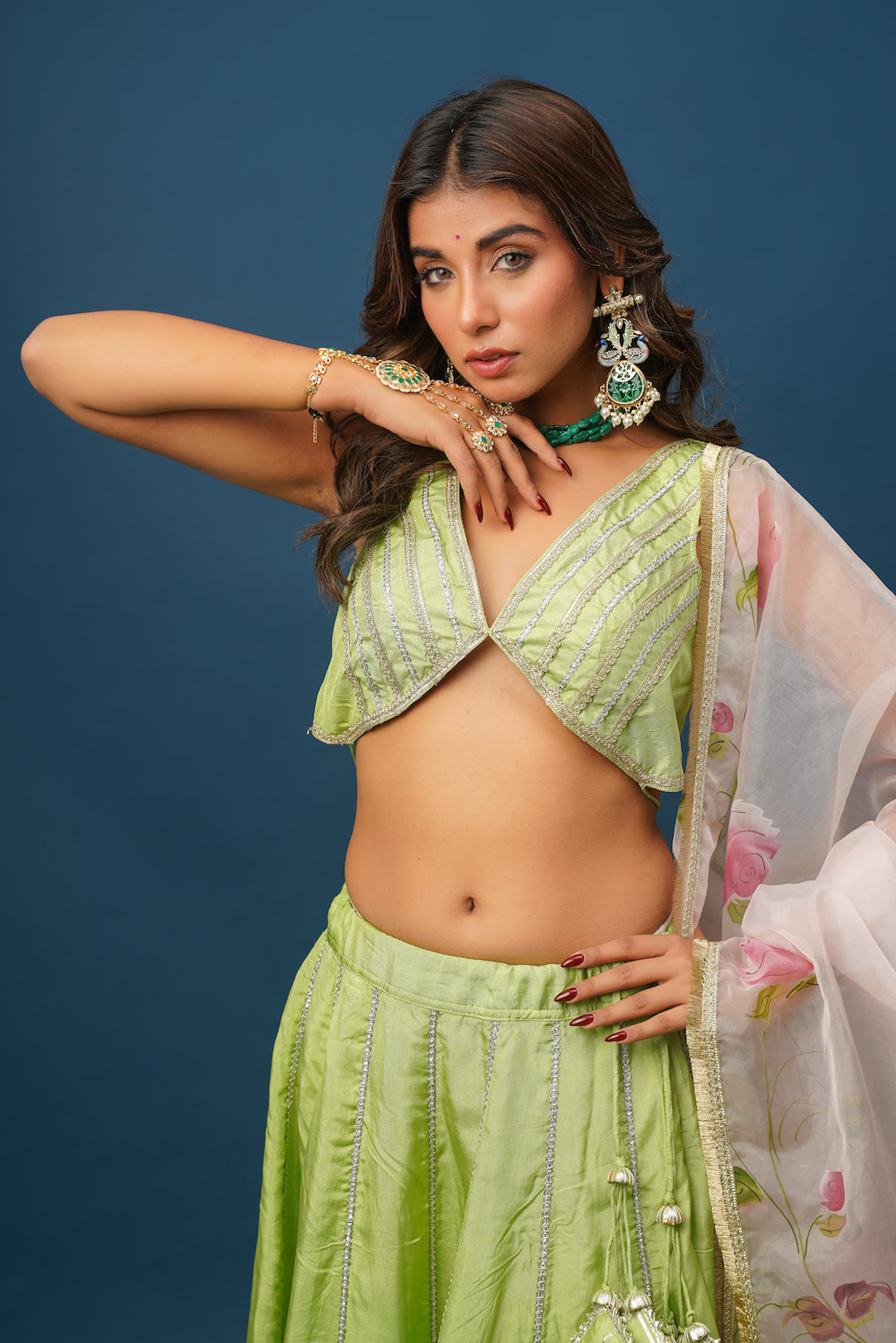 Model seated in Maya green lehenga with soft lighting