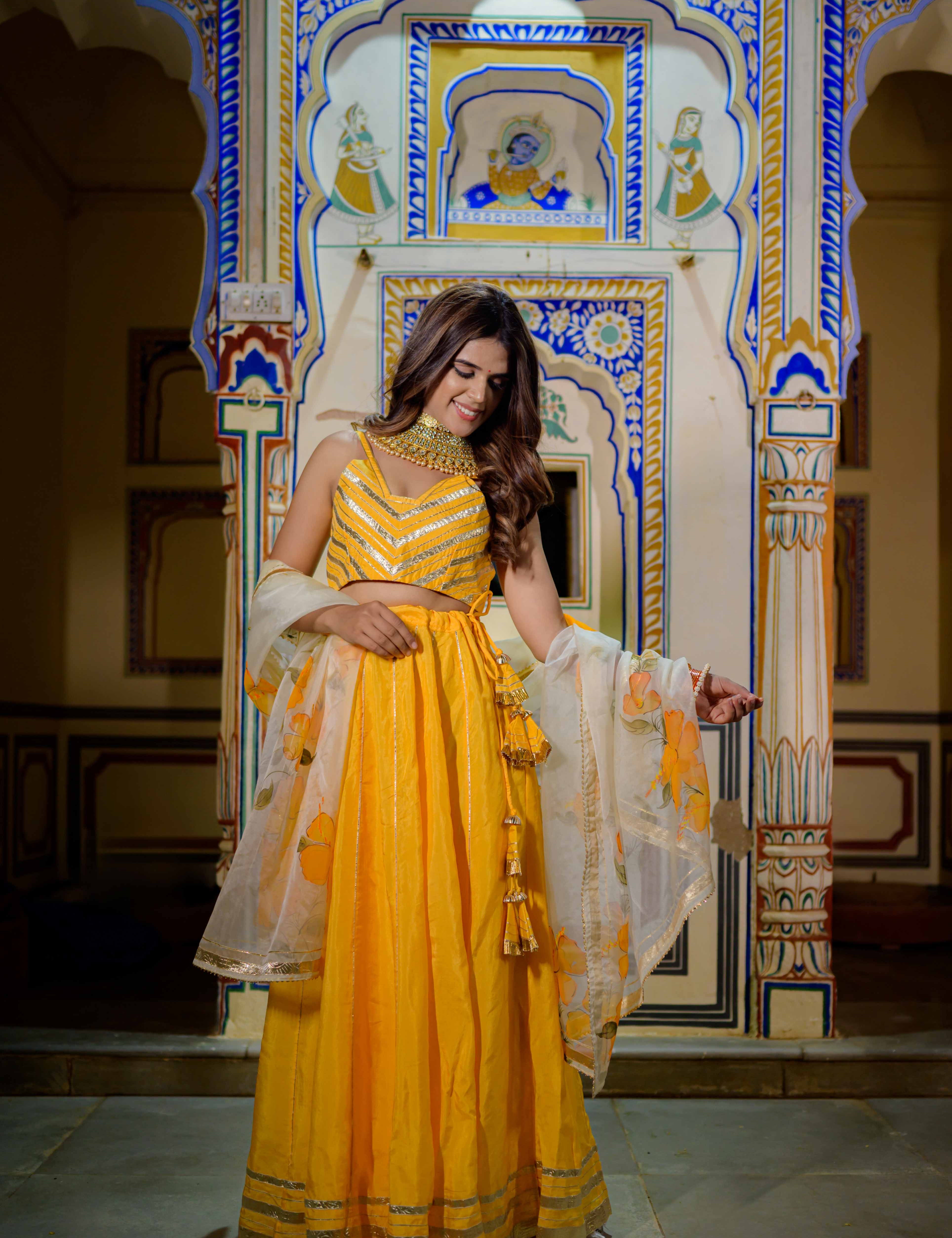 Model wearing vibrant orange lehenga for festive occasions

