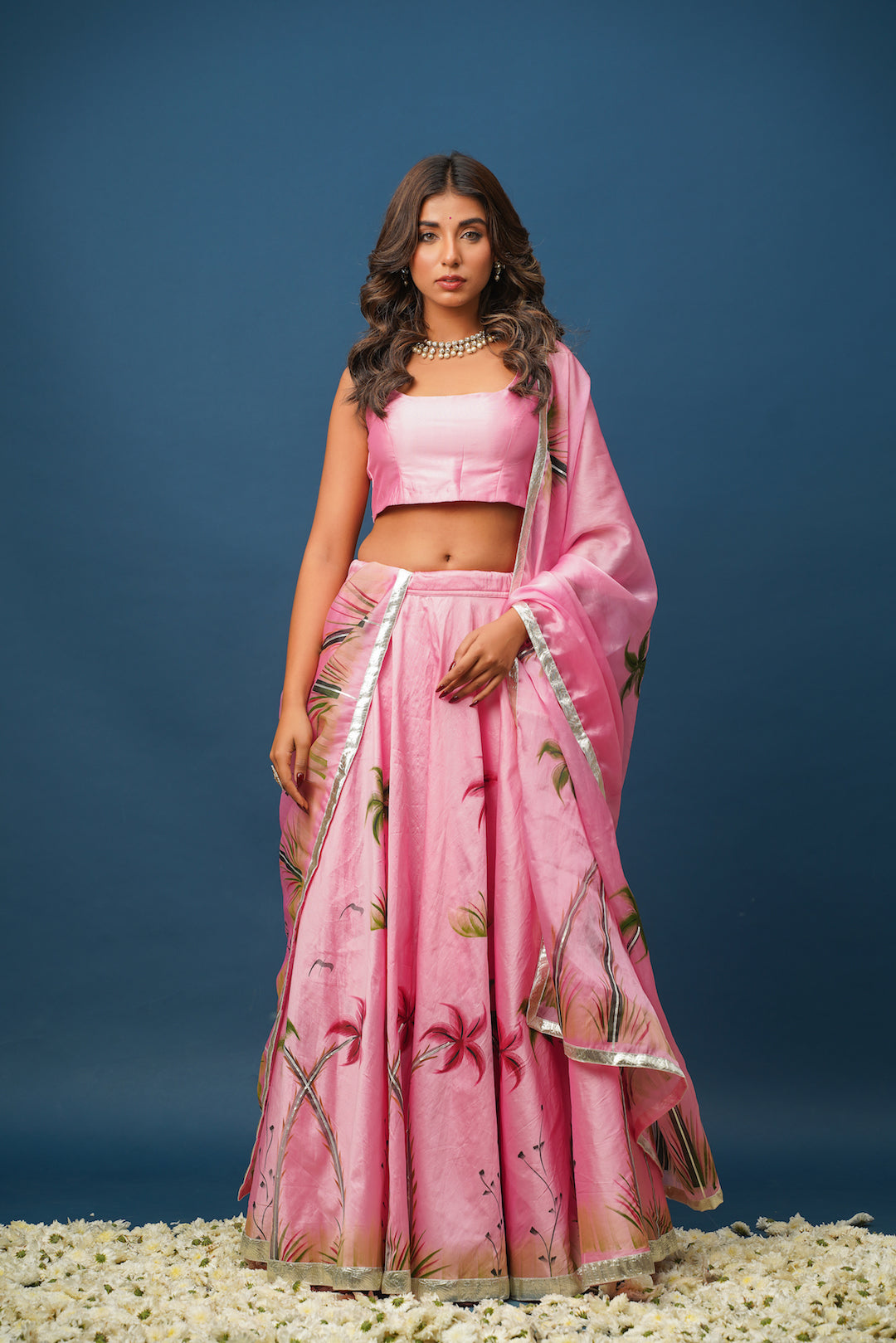 Close-up of hand-painted floral designs on pink lehenga blouse and skirt

