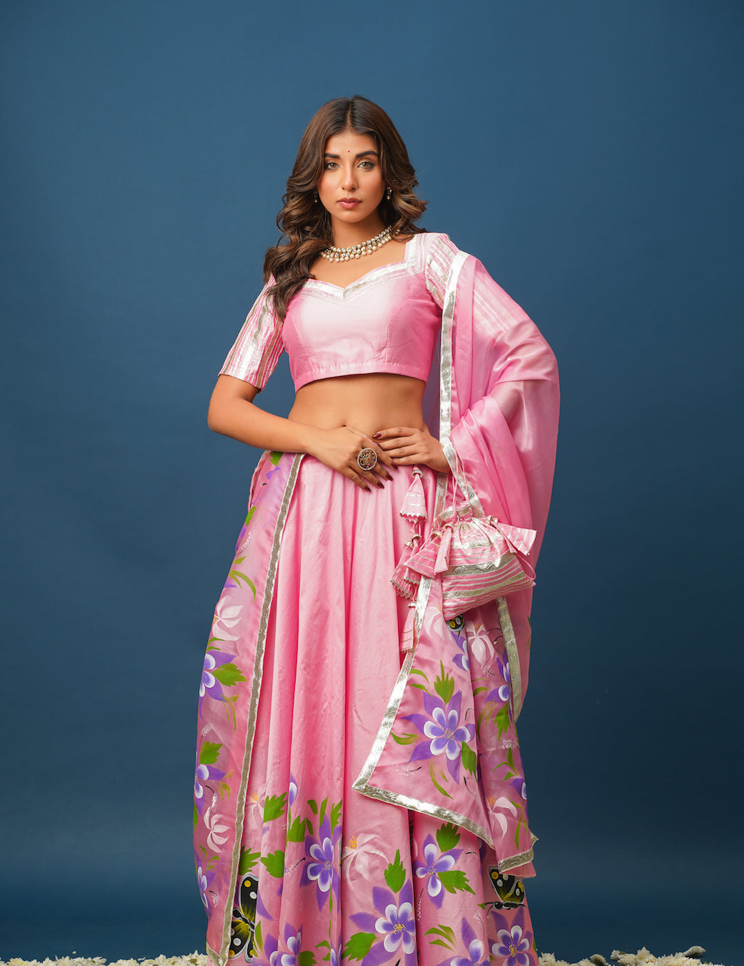 Woman wearing pink satin lehenga with hand-painted floral designs
