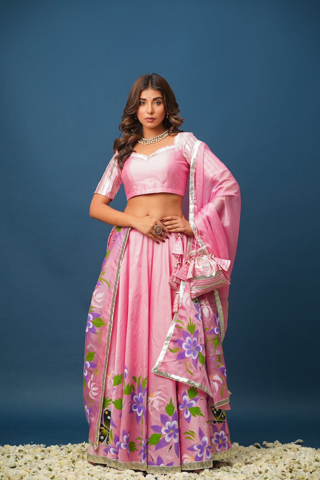 Woman wearing pink satin lehenga with hand-painted floral designs
