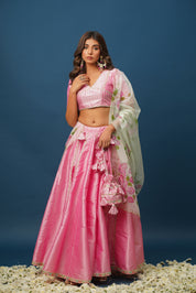 Full-length image of woman in satin pink lehenga twirling gracefully

