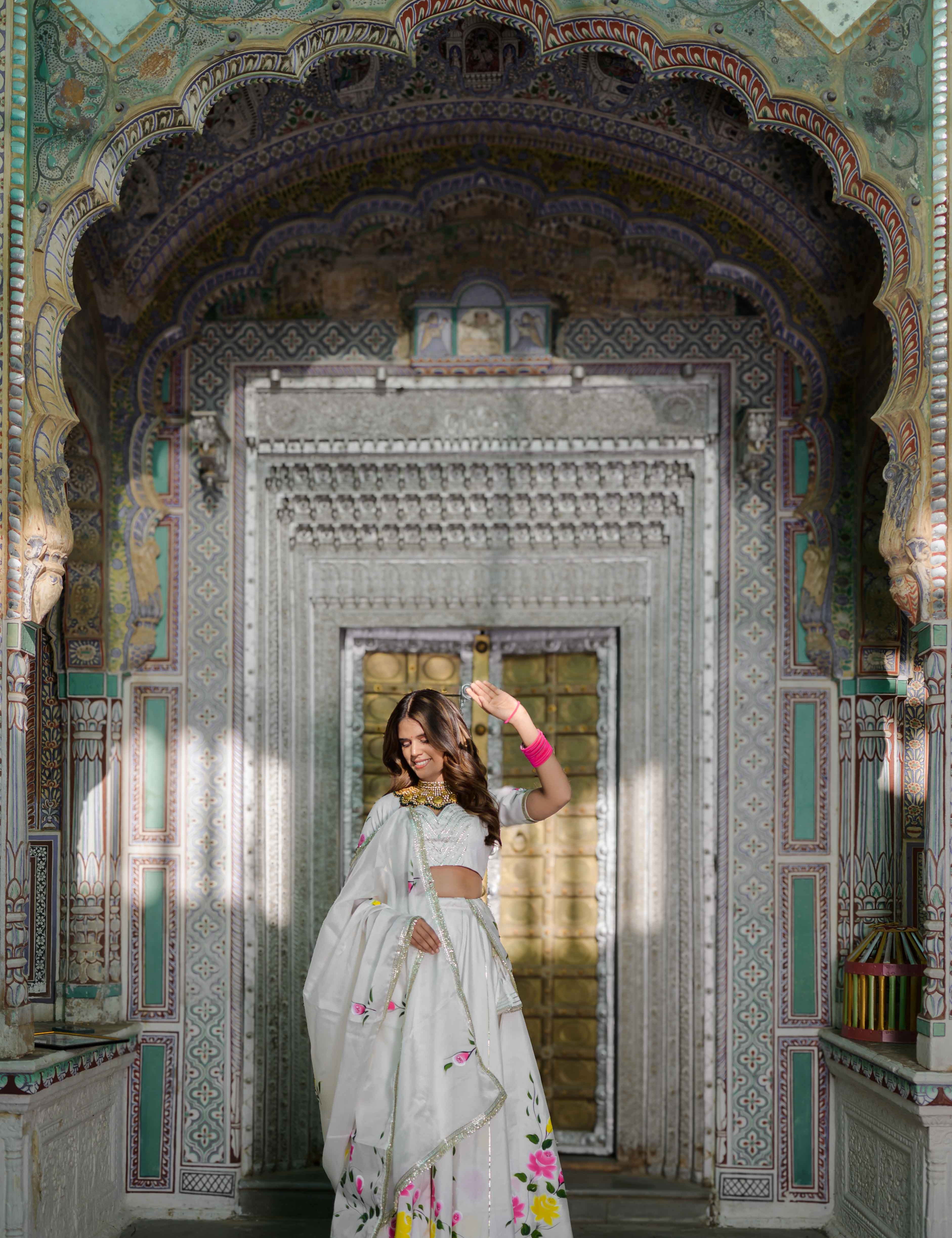 Model wearing white satin lehenga with floral hand-painted motifs

