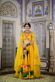 Woman twirling in yellow lehenga with floral hand-painted motifs

