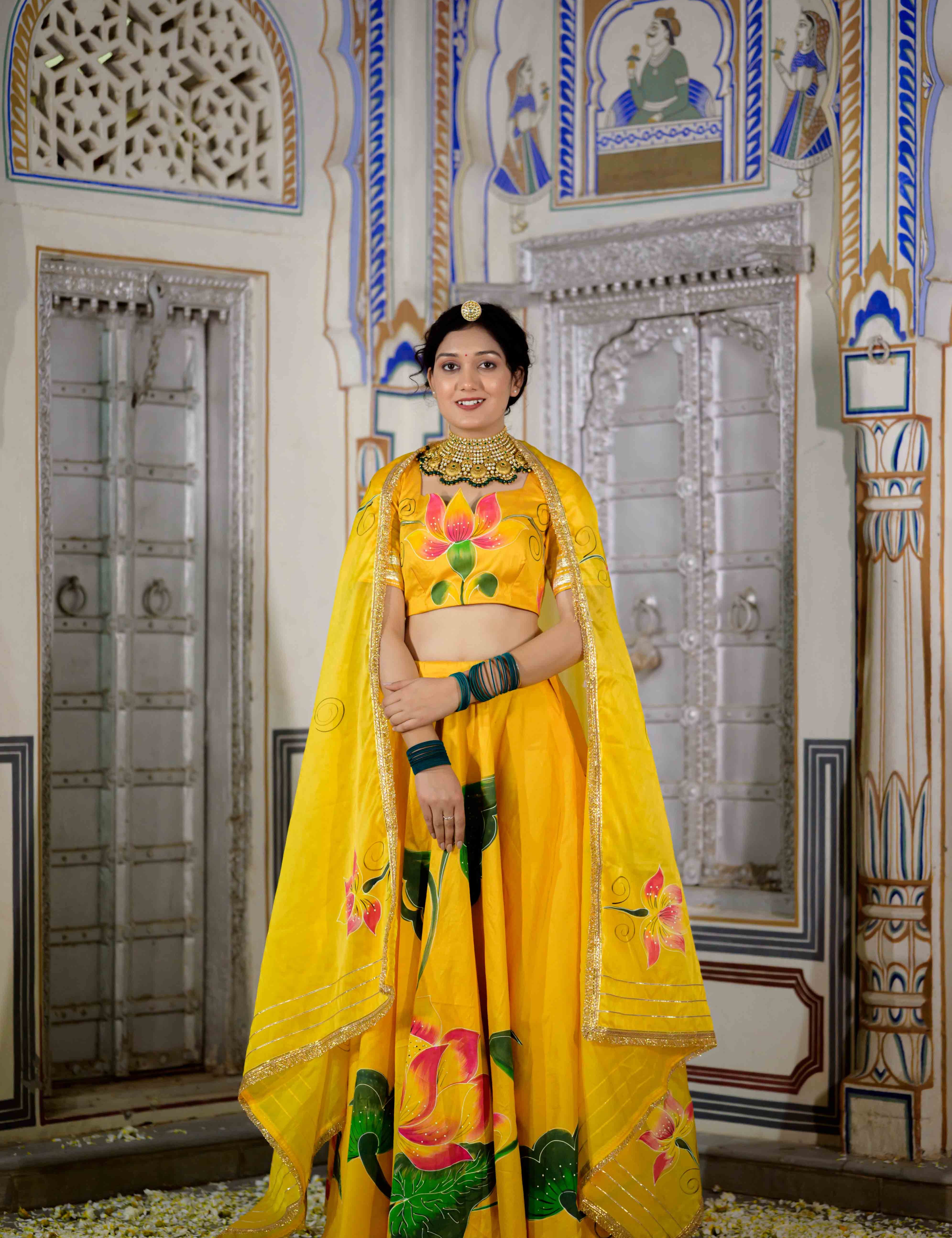 Woman twirling in yellow lehenga with floral hand-painted motifs


