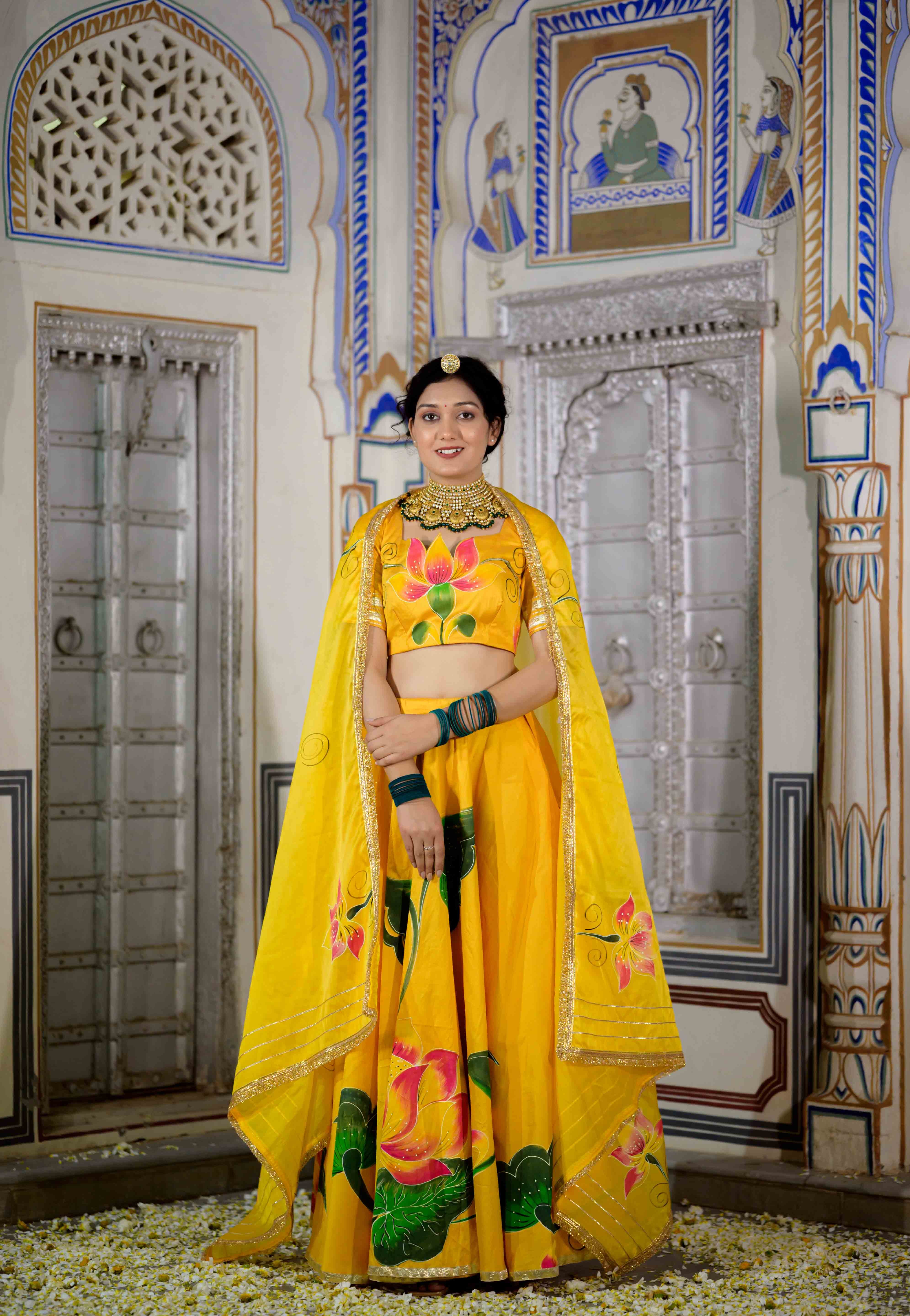 Woman twirling in yellow lehenga with floral hand-painted motifs

